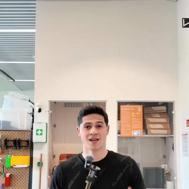 Lektor Weeks mluví do kamery v dílně s nářadím a 3D tiskárnami